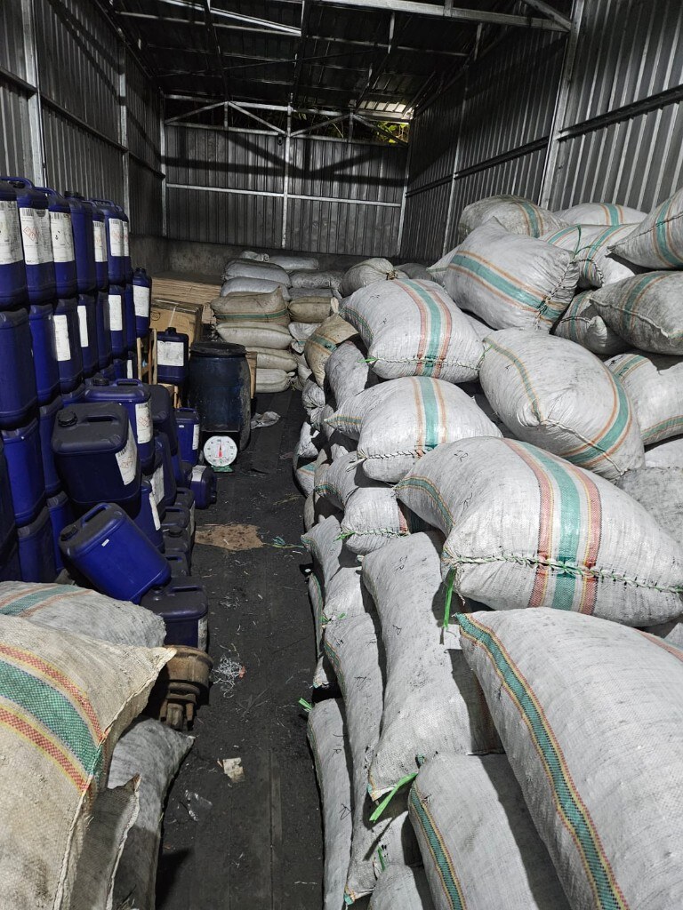 Warehouse aisle with stacked woven sacks and drums